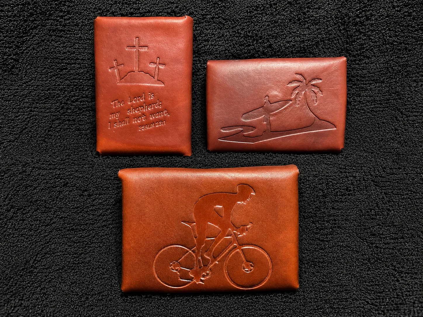 Three small leather coin purses and earbud holders with engraved designs