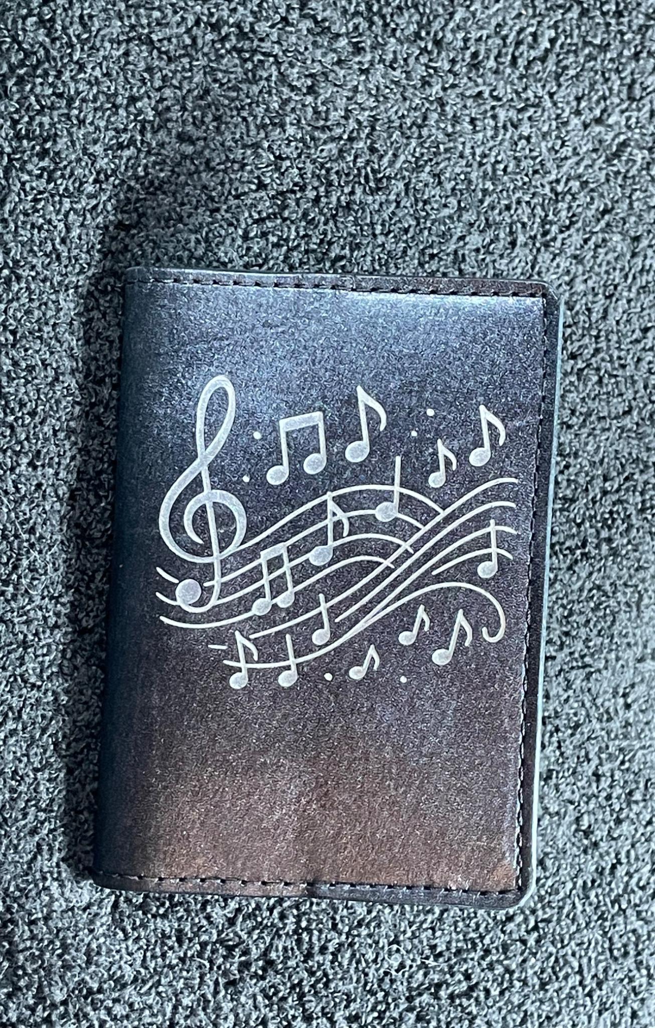 Small dark leather notebook engraved with musical notes