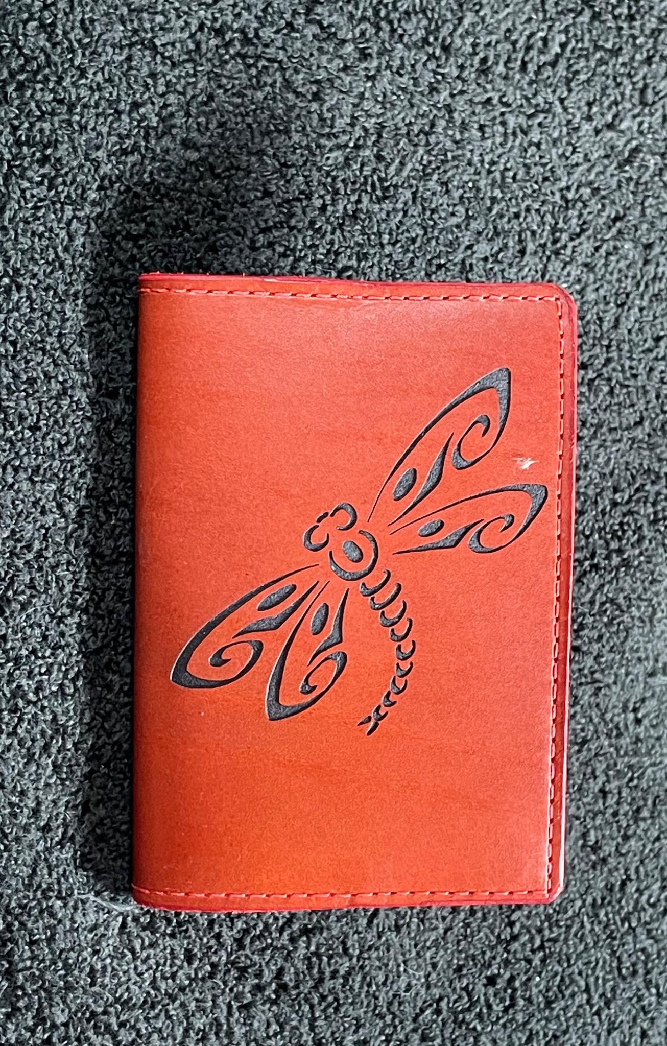 Small red leather notebook engraved with a decorative flourish
