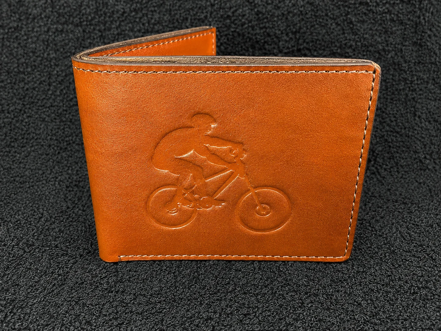 Tan leather wallet engraved with a mountain bike rider