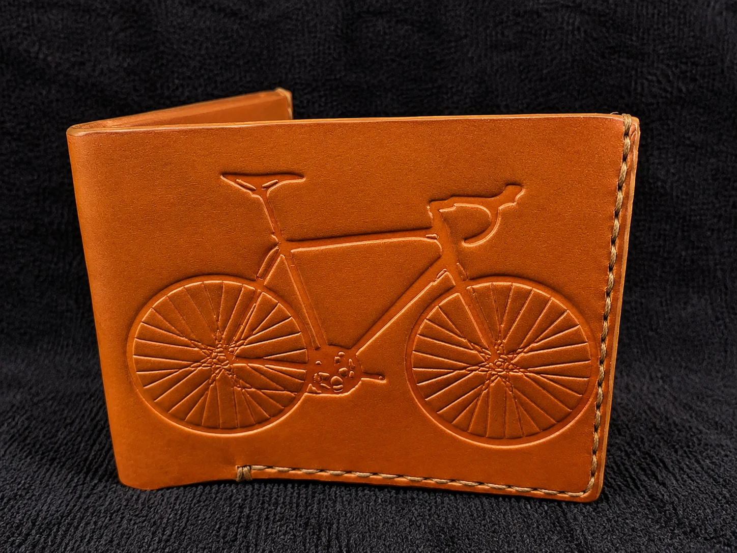 Tan leather wallet engraved with a road bicycle